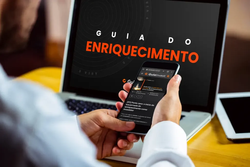 Homem observa a tela do seu Smartphone e do seu Notebook, onde podem ser visto os vídeos do curso Guia do Enriquecimento.
